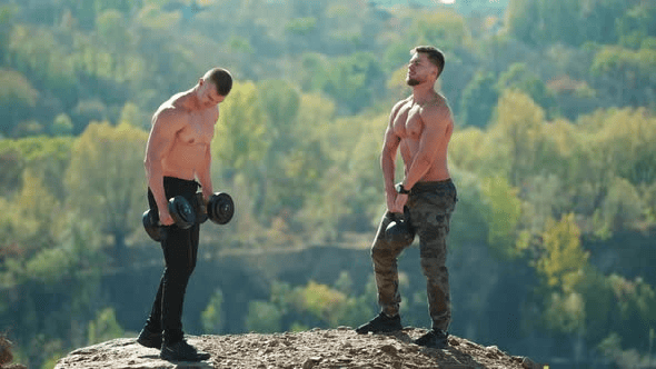 Two body builders lifting weights in the freedom off the outdoors