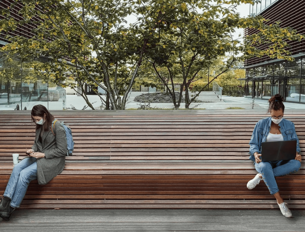 two masked people six feet apart on a bench