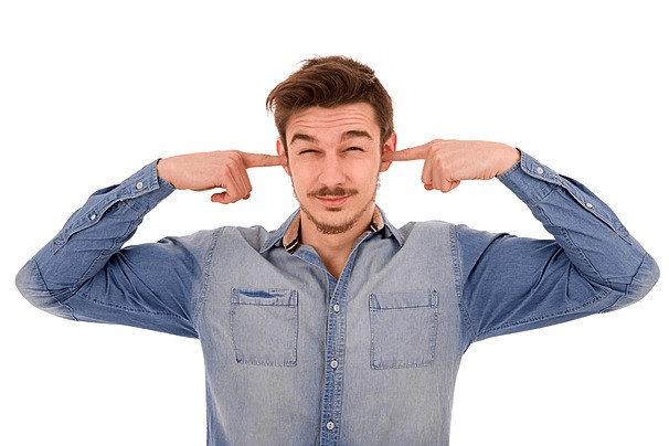 A person blocking out sound by plugging fingers in ears